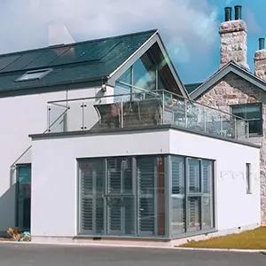 a white house with a glass balcony and a green roof